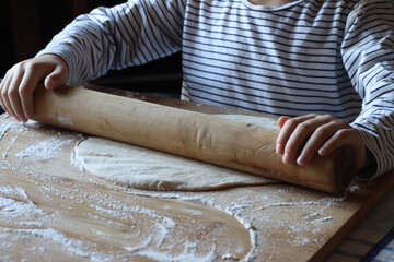 Kid making fancy pizza at home. Put mozzarella cheese mushroom on pizza dough rolling pin on a wood...