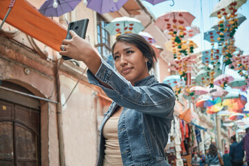 latina brunette woman on vacation taking a selfie with her cell phone in the historic streets of la...