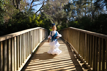 A pretty girl dancing flamenco in a typical gypsy dress with frills and fringes walks on a wooden...