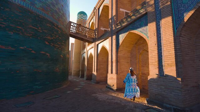 Tourist woman in ethnic dress near Kalta Minar in Ichan Kala of Khiva