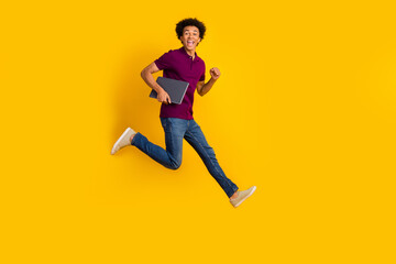 Fototapeta na wymiar Full length photo of crazy funky man wear trendy purple polo carrying netbook hurrying store isolated on yellow color background