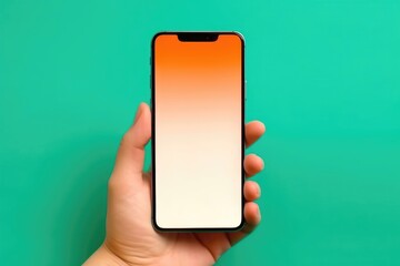 Modern bezel-less smartphone with blank orange gradient screen held against green background