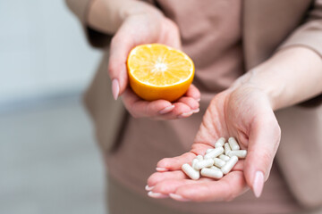  pills in one hand and an orange in the other