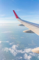 Fototapeta premium View from the airplane window at a beautiful cloudy sky and the airplane wing