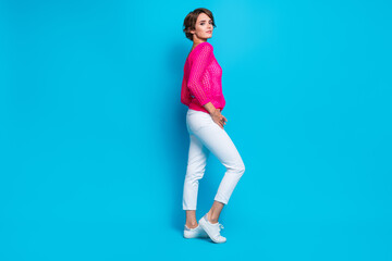 Fototapeta na wymiar Full length photo of shiny pretty woman wear knitted neon shirt walking empty space isolated blue color background