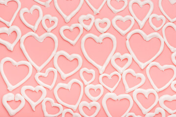 sweet meringue kiss cookies of heart shapes over pink background, concept of St. Valentines Day