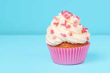 trendy cupcake with sprinkles on blue background, concept of St. Valentines Day, copy space