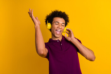 Photo of positive energetic man closed eyes wear stylish purple clothes listen music quality device isolated on yellow color background