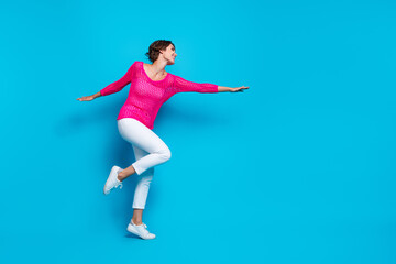 Fototapeta na wymiar Full length photo of positive sweet woman wear knitted neon shirt hands arms sides flying empty space isolated blue color background