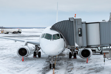 White passenger aircraft at the jetwalk at winter airport apron