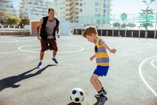 Fototapeta Father and son playing soccer at an outdoor court