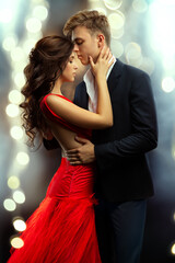 Couple Embracing in Love. Beautiful Girl and Handsome Man dancing in Romantic Hug over shining Lights Background. Boyfriend kissing Lady Side View