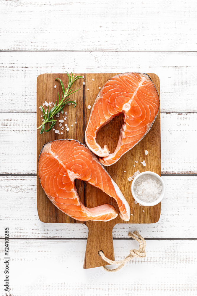 Sticker fresh raw salmon steaks on a board with ingredients for cooking, top view