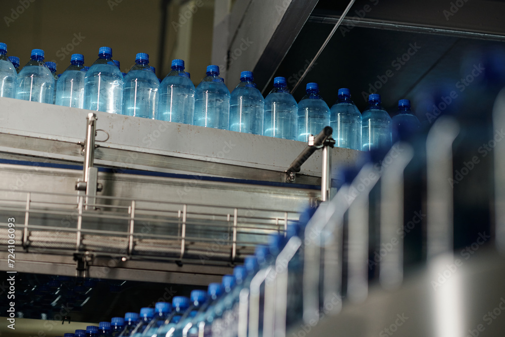 Aufkleber row of capped plastic bottles with still and carbonated mineral water moving on huge assembly line a