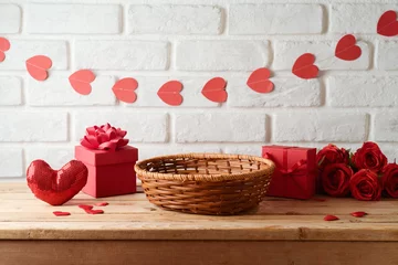 Fotobehang Empty basket on wooden table with gift box and heart shape garland over brick wall background.  Valentine's day mock up for design and product display © maglara