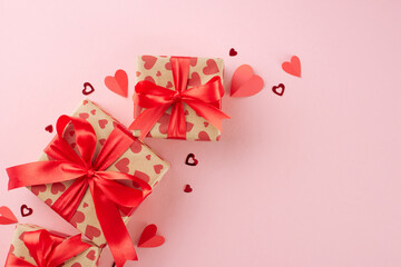 Surprises from the heart: valentine's day gift inspiration. Top view composition of festive gift boxes, hearts on pastel pink background with advert space