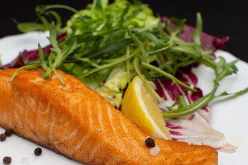 Grilled salmon steak with lemon and herbs on a white plate