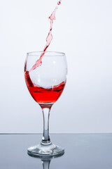 Red wine poured into a glass on a white background