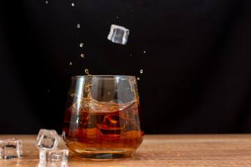 Ice cubes falling into a glass of whiskey