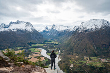 Traveler with his back turned, hands open, enjoying a mountain landscape in the Norwegian fjords of...