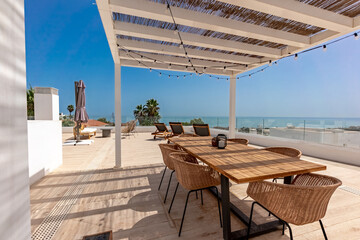 a luxury rooftop terrace with large wooden table and mediterranean sea views 