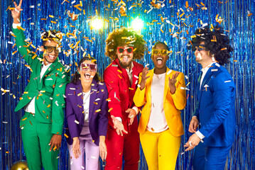 Funny group of happy young people dressed in bright business suits, curly wigs and colorful large...