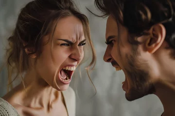 Fotobehang Angry young adult Caucasian woman yelling versus her husband on grey background, Young couple arguing and fighting. Domestic violence and emotional abuse scene of woman and man screaming at each other © useful pictures