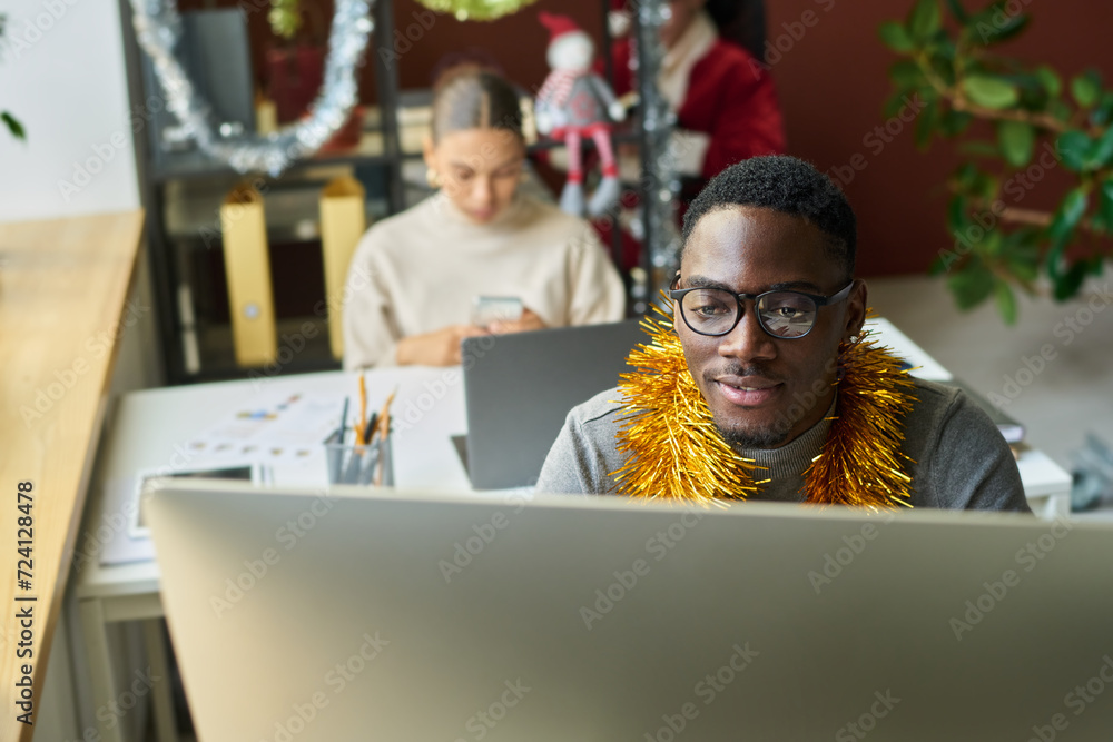 Aufkleber young african american businessman looking at computer screen while analyzing online data against fe