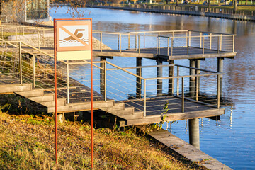 A sign prohibiting swimming in the pond stands on the shore