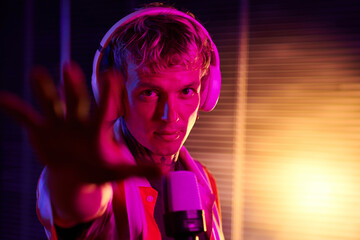 Portrait of singer in headphones recording song in studio with neon lights