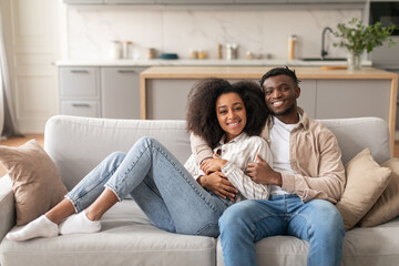 Obraz premium Romantic African Couple Hugging While Chilling On Couch At Home