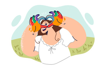 Little girl artist with palms covered with paint shows heart gesture from fingers, standing on lawn