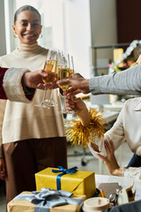 Happy young intercultural white collar workers with flutes of champagne toasting for new business during Christmas party in office