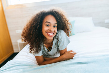 Portrait of woman with curly hair lying on bed