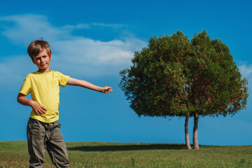 Boy points to the tree on a sunny day, ecology concept