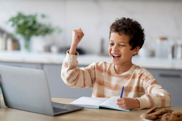 Little Black Schoolboy Using Laptop And Celebrating Success At Home