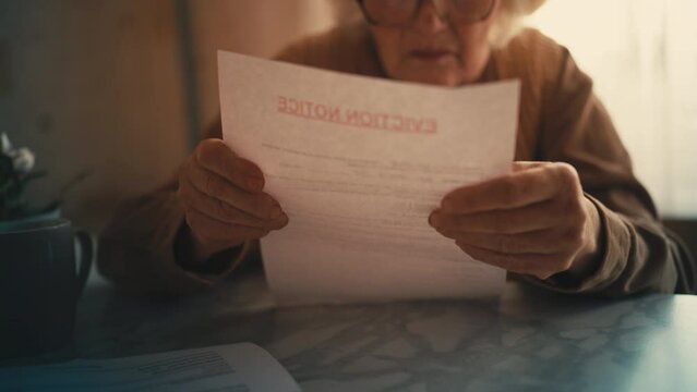 Old woman opening eviction notice letter, shocked with news, financial crisis