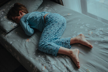 Boy in pajamas sleeping in bed without blanket