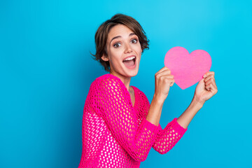 Photo of impressed funky woman wear knitted neon shirt rising pink heart postcard isolated blue...