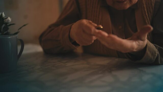 Senior woman counting coins in palm, financial crisis and poverty, low pension