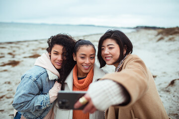 Young and diverse group of female friends taking a selfie on a sandy beach