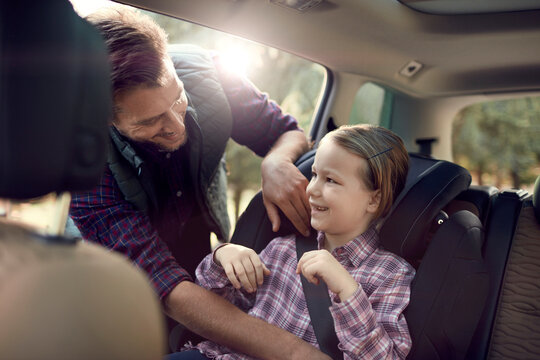 Father putting daughter in a child seat in a car