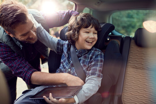 Father putting son in a child seat in a car