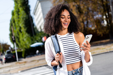 Photo of glad positive adorable girl wear crop top white shirt striped clothes writing sms waiting meeting in park september outdoors