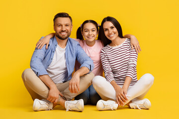 Caucasian family with teen daughter sitting on floor and smiling towards camera