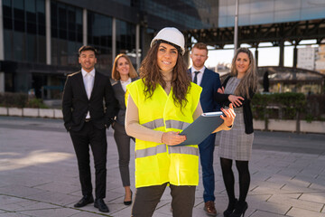 female architect looking at camera with engineers employees behind