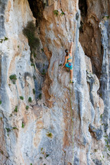 A young and strong woman is rock climbing on a rock.