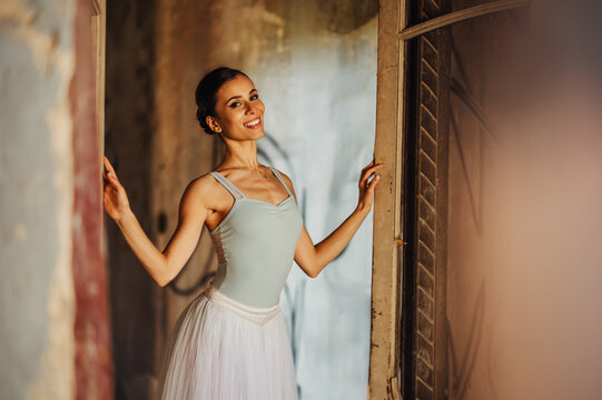 A happy ballerina standing on doorway in rustic interior.