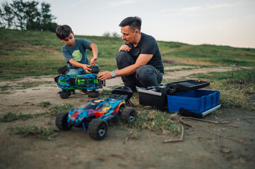 Quality playtime of father and his son outdoors, fixing toy race cars.