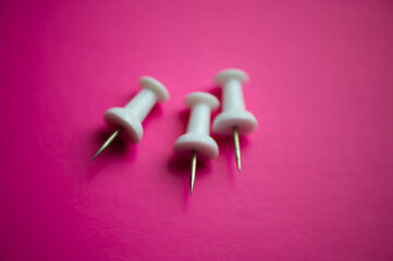 Three white pushpins on pink, close -up.